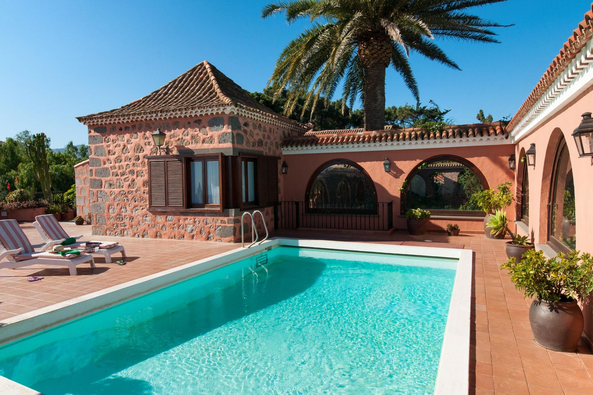 Casa rural con piscina y plameras de fondo