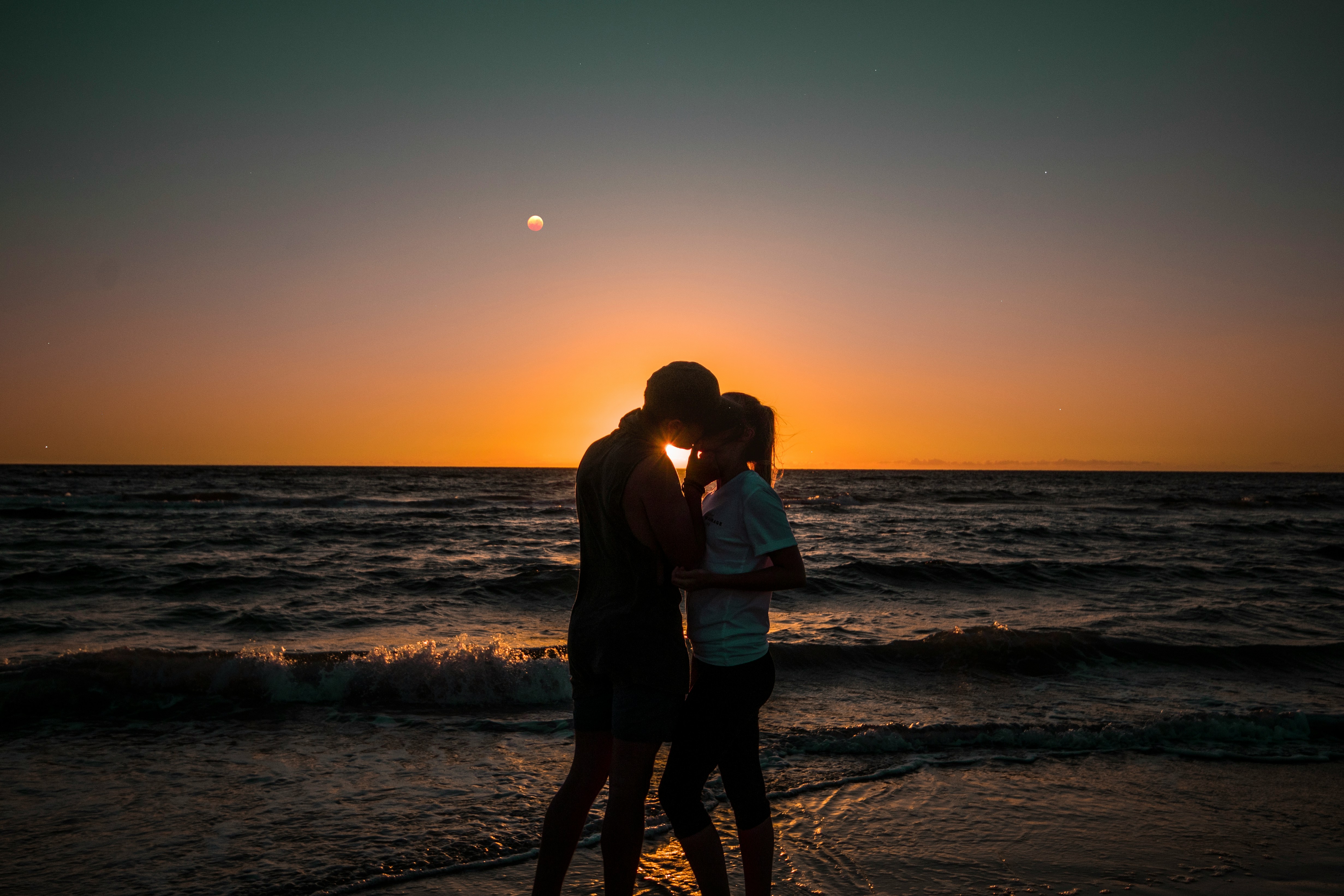 paar küsst sich am strand mit sonnenuntergang